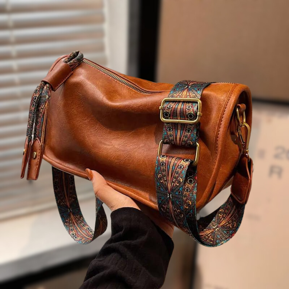Women's stylish shoulder bag with a soft, textured finish, featuring a zippered closure and an adjustable patterned strap for a chic and versatile look.