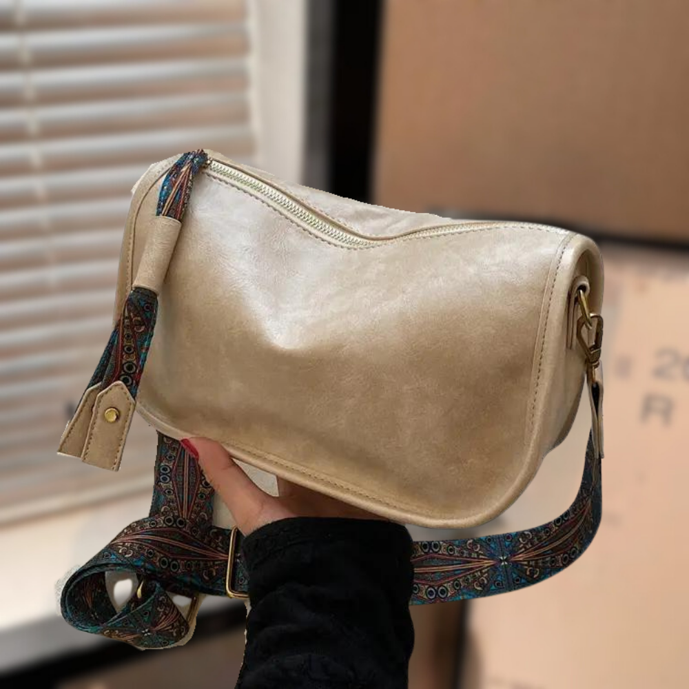Women's stylish shoulder bag with a soft, textured finish, featuring a zippered closure and an adjustable patterned strap for a chic and versatile look.